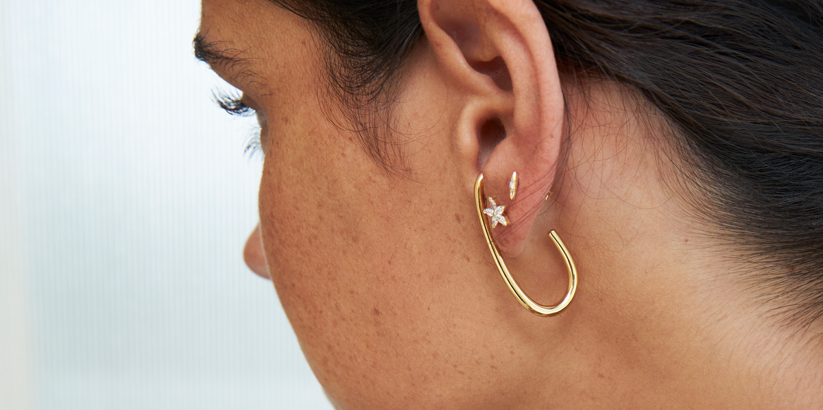A woman wearing elegant gold hoop earrings while considering buying jewelry on Black Friday.
