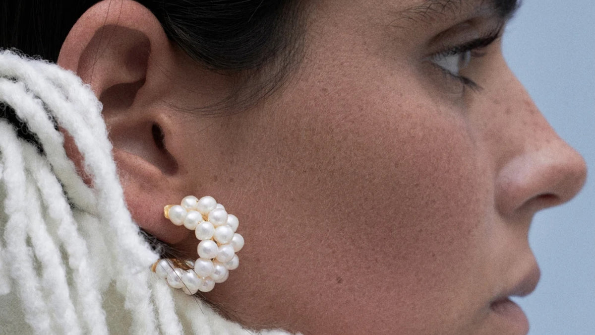 Close-up of a woman wearing pearl earrings, featured in the cultured pearls guide by CINCO Jewelry.