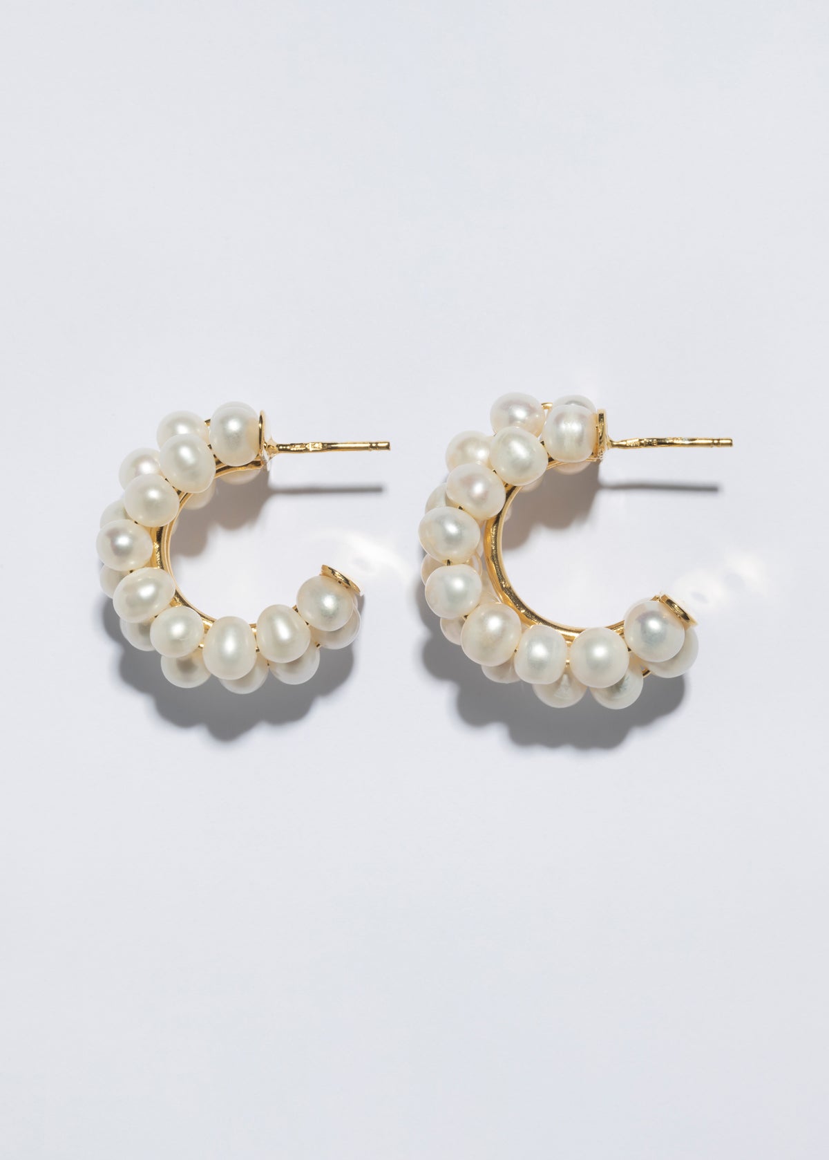 Handmade pearl earrings in sterling silver featuring elegant hoops adorned with white pearls.