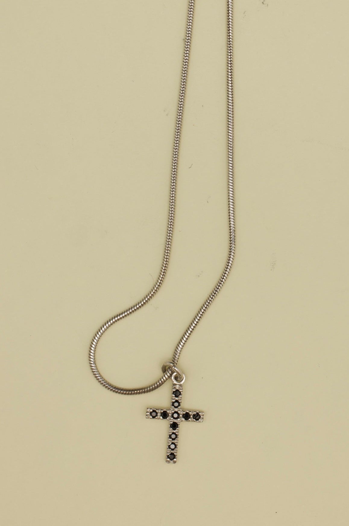 Silver cross necklace on a beige background