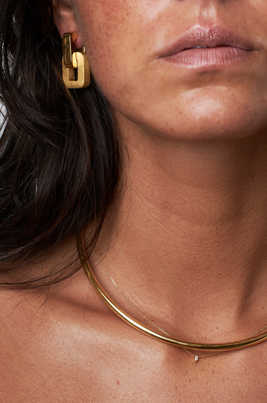 Close-up of a woman wearing gold earrings and necklace.