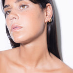 model wearing amina huggies white, norma earrings white and  jodie huggies in gold