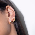 model wearing amina huggies white, norma earrings white and  jodie huggies in gold