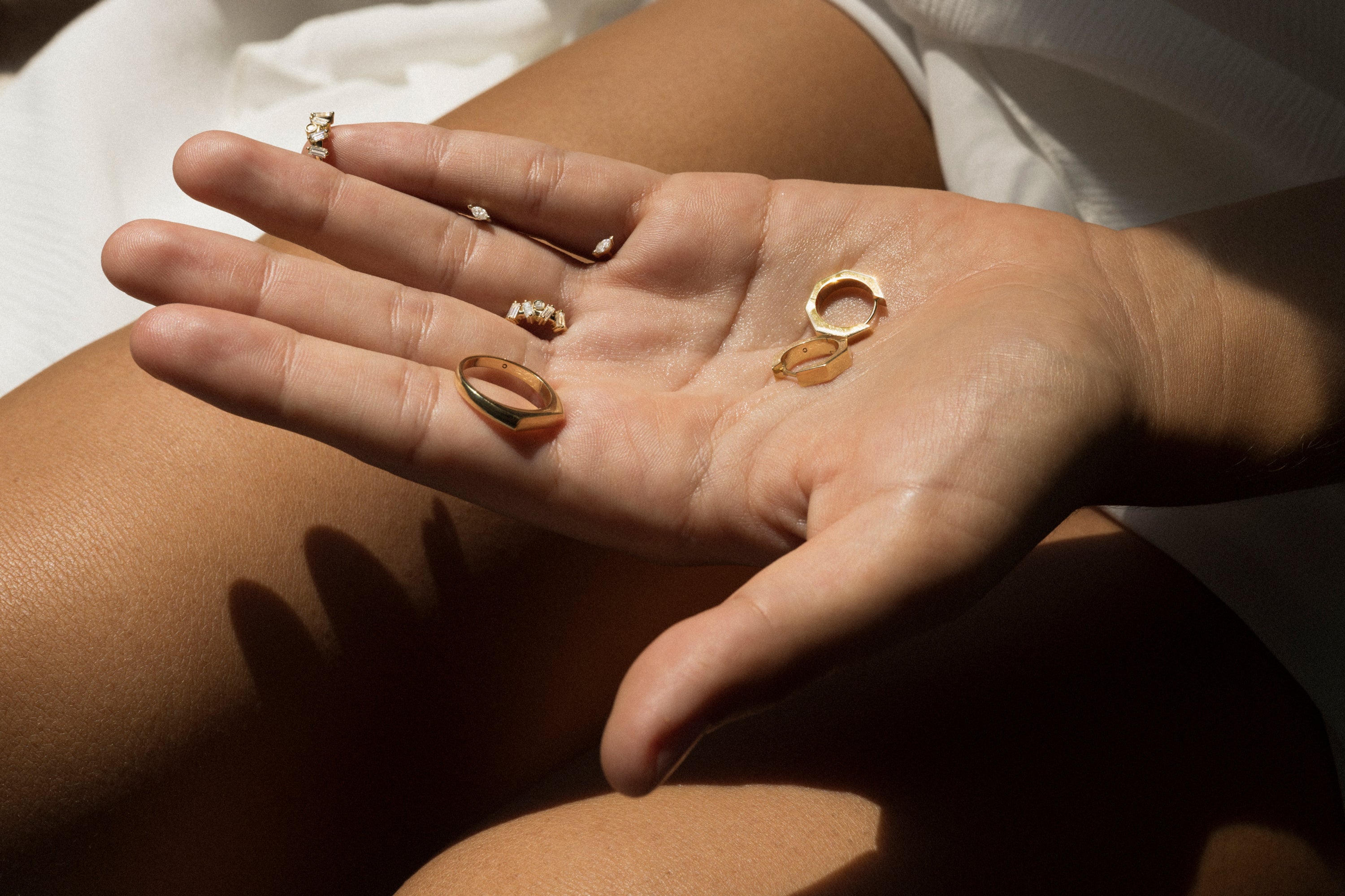 Mano sosteniendo tres anillos de oro con un fondo neutro