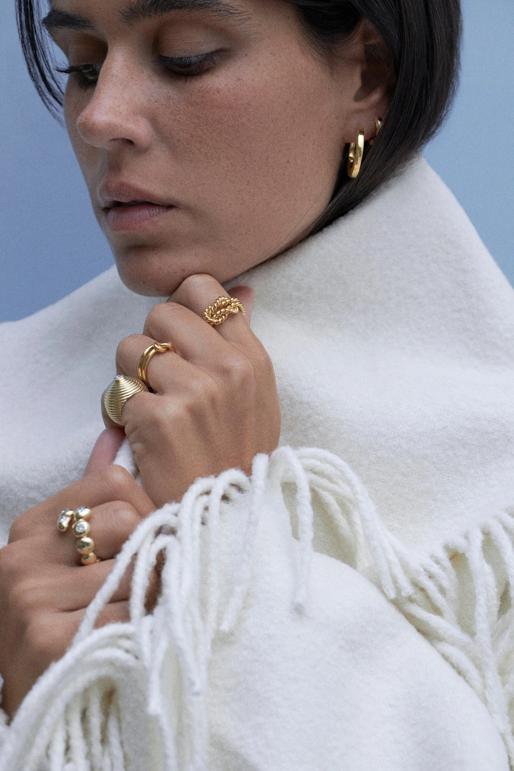 model wearing multiple rings and engravable hoops earrings