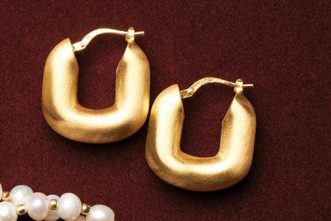 Gold hoop earrings on a burgundy background