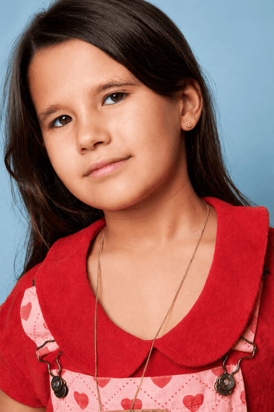 Joven con una camiseta roja y un delantal con estampado de corazones sobre un fondo azul