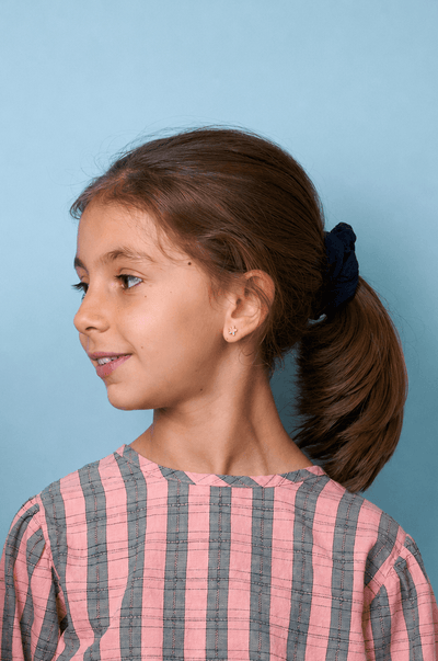 Niña joven con una camiseta de rayas rosas y grises sobre un fondo azul