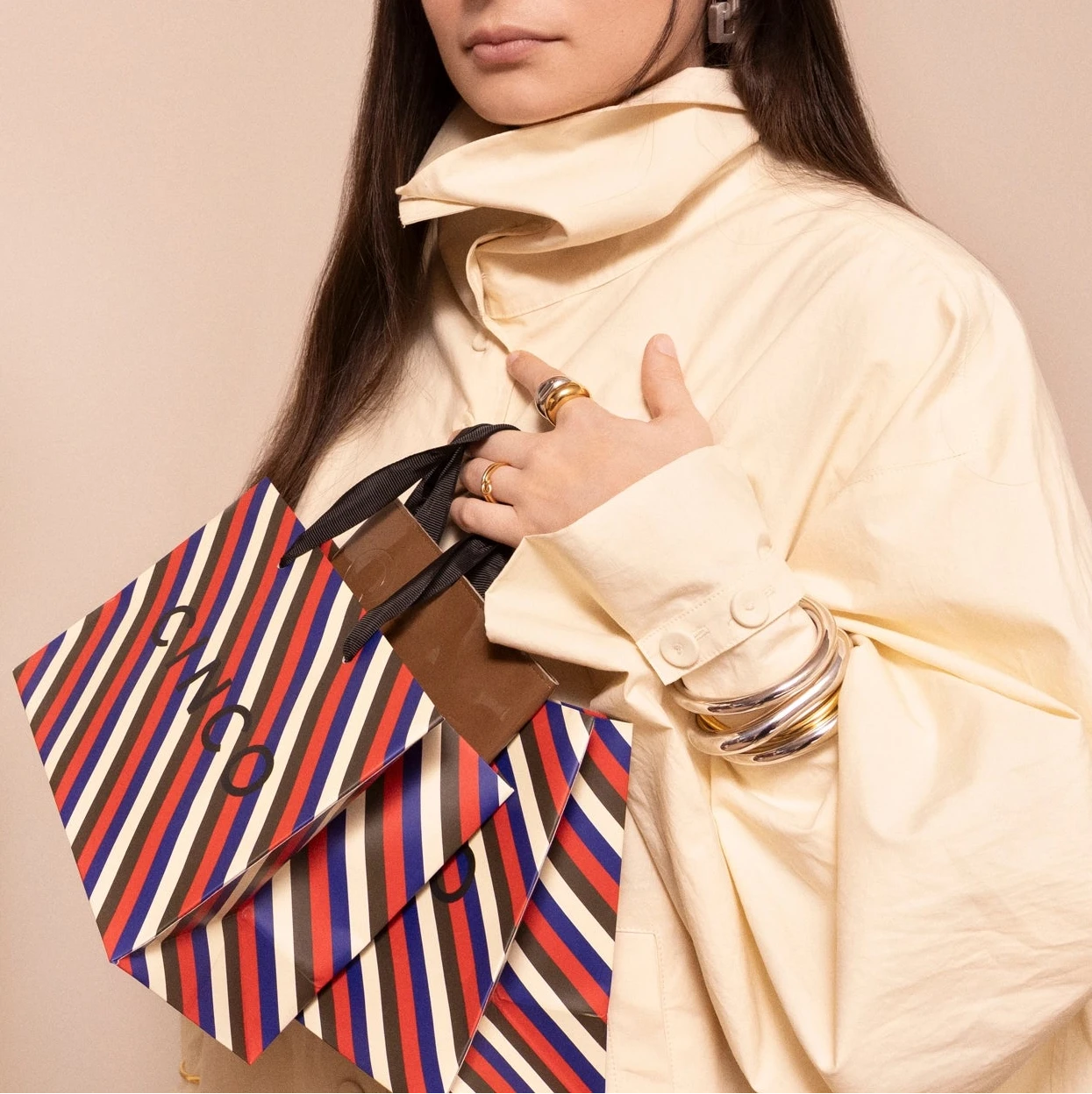 Mujer sosteniendo una bolsa rayada CINCO con joyas de compra con descuento